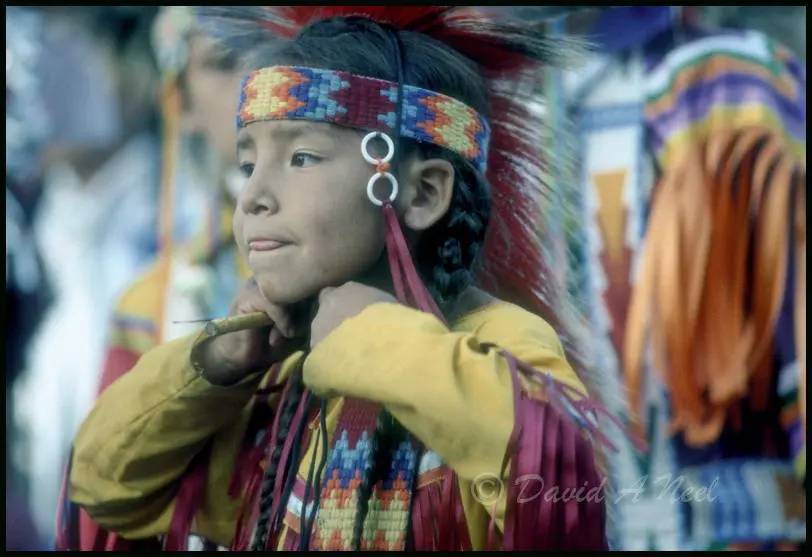 A young Native boy concentrates on getting dressed to dance.