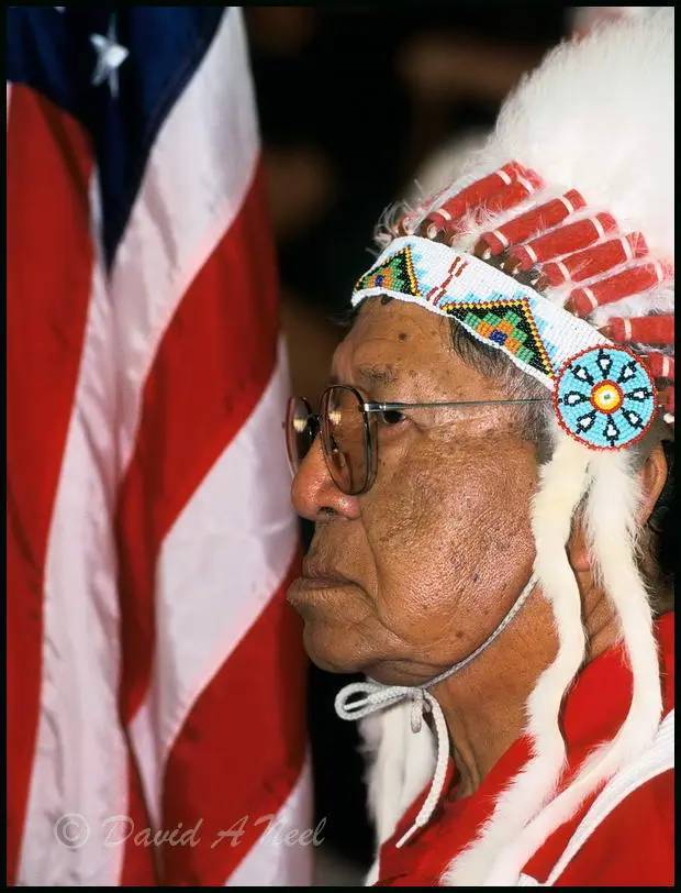 A Native American chief carries the American flag in a Grand Entry ceremony.